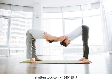 Young Couple Doing Flexibility Workout In Yoga Studio Together