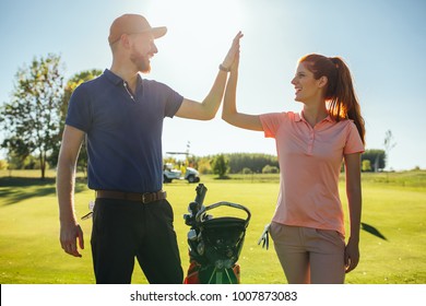 Young couple doing a high five on the golf coarse - Powered by Shutterstock