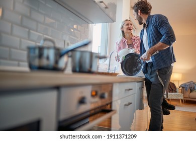 A young couple doing housework with satisfaction in a cheerful atmosphere. Kitchen, housework, home, relationship - Powered by Shutterstock