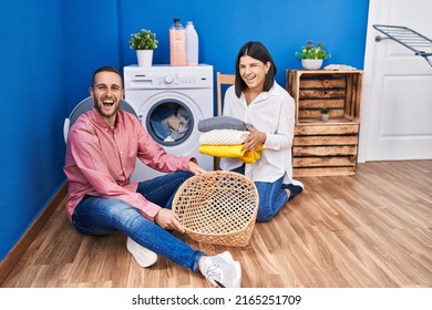 Young Couple Doing Laundry At Home Smiling And Laughing Hard Out Loud Because Funny Crazy Joke. 