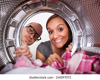 Young Couple Doing Laundry View From The Inside Of Washing Machine. 