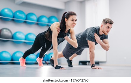 Young couple doing push-ups from the floor on one hand together on the background of fitness balls. Sporty male and female in sportswear training in the sports club. - Powered by Shutterstock