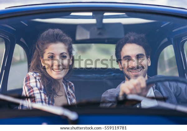 Young couple doing a road trip in Tuscany countryside\
in a vintage car