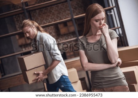 Young couple is drifting apart after breakup, man is carrying his stuff in cardboard boxes