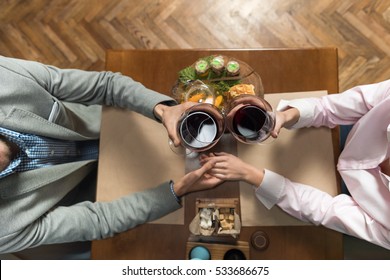 Young Couple Drink Wine Sitting Restaurant Table, Romantic Date Man And Woman Hold Glasses Clink Toasting Top Angle View