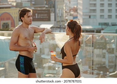 Young Couple Drinking Cocktails And Talking At Rooftop Swimming Pool Party