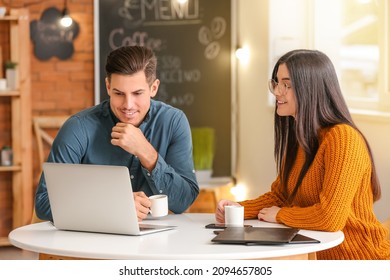 Young couple drinking coffee while working with laptop in cafe