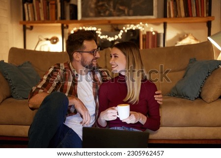 Young couple drinking tea while sitting in the living room at night