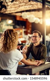 Young Couple Drinking Wine And Having Fun During Lunch In A Bar. Focus Is On Man. 