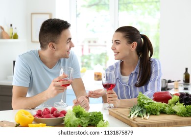 Young couple drinking wine while cooking together in kitchen - Shutterstock ID 1131875879