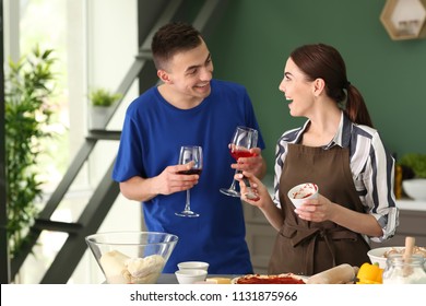 Young couple drinking wine while cooking together in kitchen