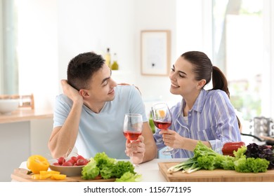 Young couple drinking wine while cooking together in kitchen