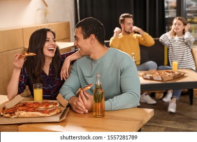 Young Couple Eating Delicious Pizza In Cafe