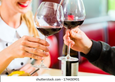 Young couple eating fast food and drinking red wine in a American retro fast food diner - Powered by Shutterstock