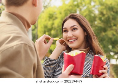 Young Couple Eating French Fries In Park