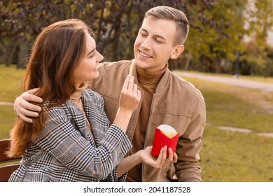 Young Couple Eating French Fries In Park