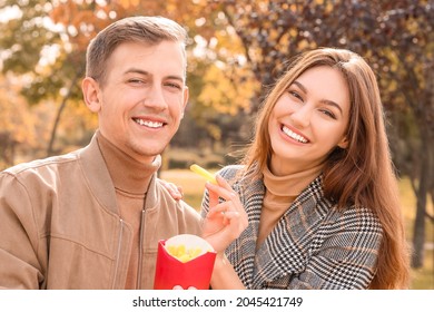 Young Couple Eating French Fries In Park