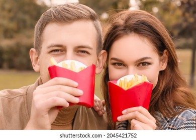 Young Couple Eating French Fries In Park