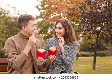 Young Couple Eating French Fries In Park