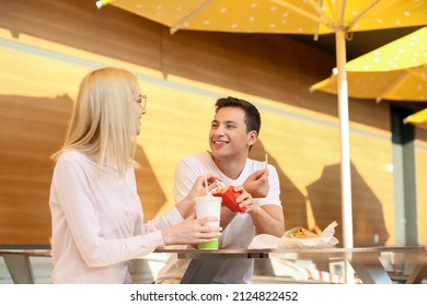 Young Couple Eating French Fries In Cafe Outdoors