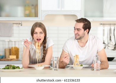 Young Couple Eating Pasta On Kitchen Table