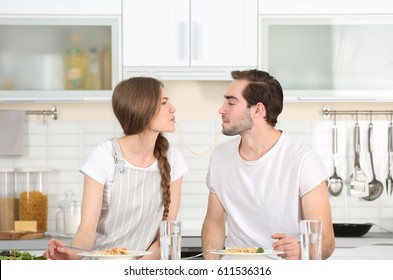 Young Couple Eating Pasta On Kitchen Table