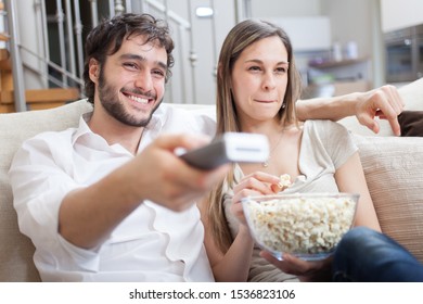 Junge Ehepaare, die Popcorn essen, während sie sich einen Film ansehen