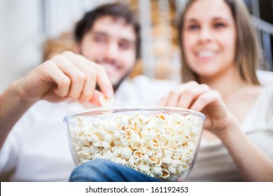 Young Couple Eating Popcorn While Watching A Movie