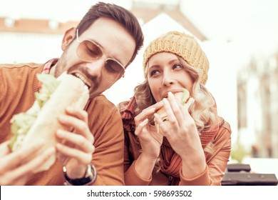 Young Couple Eating Sandwich Outdoors.