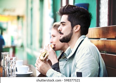 Young couple is eating sandwiches and enjoying.