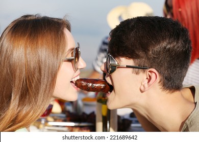 Young Couple Eating Sausage On Picnic, Outdoors