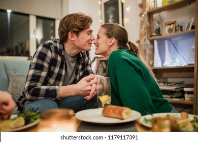 Young Couple Are Eating Spaghetti At A Dinner Party And Are Sharing One Strand.