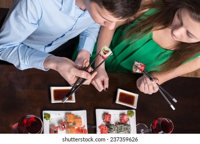 Young couple are eating sushi at restaurant. Top view.