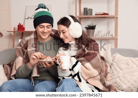 Young couple eating treats at home on winter day