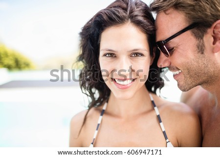 Young couple embracing each other near pool at sunny day