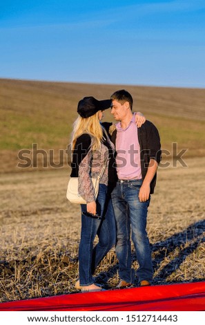 young couple embracing in a field looking each other in the eye
