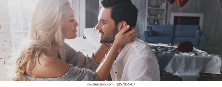 Young couple embracing and looking at each other with smile while spending time indoor - Shutterstock ID 2257856907