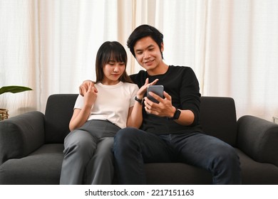 Young Couple Embracing And Shopping Online On Internet Via Smart Phone. People And Technology Concept