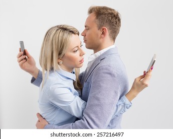 Young couple embracing and still using their mobile phones