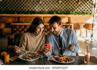 A young couple enjoy eating meals and surfing the net on smartphone - Powered by Shutterstock