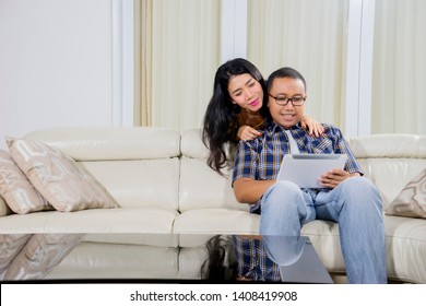 Young couple enjoying leisure time together while using a digital tablet in the living room