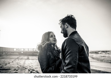 Young Couple Enjoying The Outdoor Leisure Activity At The Romantic Beach In Autumn Season - Strong Black And White Editing In Vintage Style With Focus On Man At Right