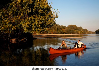 Young couple enjoying a trip in a canoe - sunset light - Powered by Shutterstock