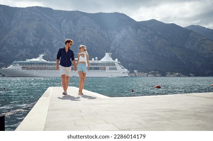 A young couple enjoying a walk on the dock on a beautiful day while spending a holiday on the seaside. Love, relationship, holiday, sea - Powered by Shutterstock