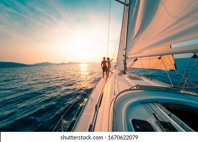 Young Couple Enjoys Sailing In The Tropical Sea At Sunset On Their Yacht.