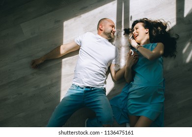 Young Couple Expecting Baby Laying On The Beam Of Light With A Dog Indoors