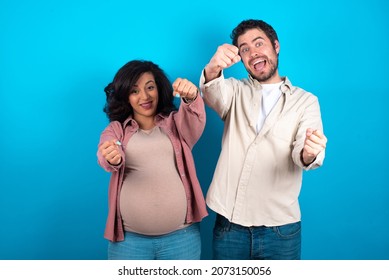 Young Couple Expecting A Baby Standing Against Blue Background Imagine Steering Wheel Helm Rudder Passing Driving Exam Good Mood Fast Speed