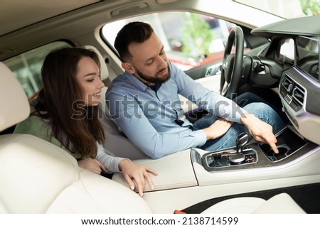 young couple exploring additional options when buying a new car at a car dealership