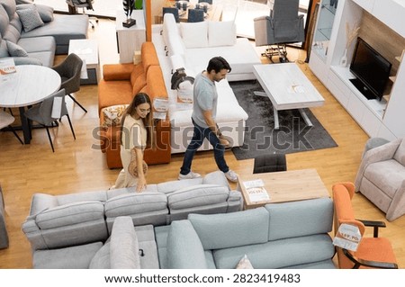 Young couple exploring different sofas and tables in a modern furniture store