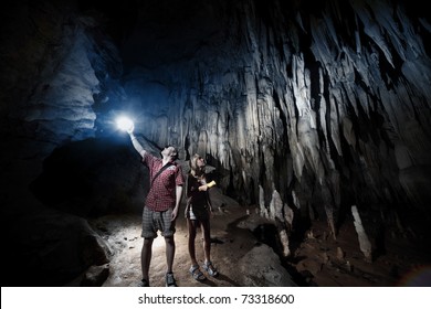 Young couple exploring huge cave with torches - Powered by Shutterstock